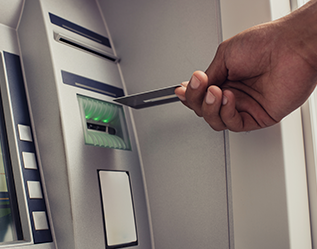A person inserting a credit card into an atm machine.