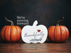 Three pumpkins with the words we're moving forward thankful.