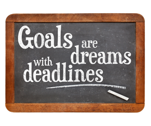 A chalkboard with the words goals are with deadlines.
