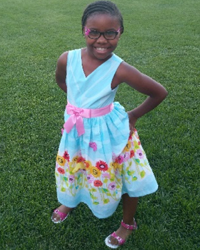 A young girl wearing glasses and a blue dress.