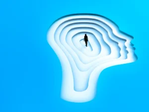 Silhouette of a person standing inside a layered, head-shaped structure against a blue background, symbolizing mental wellness.
