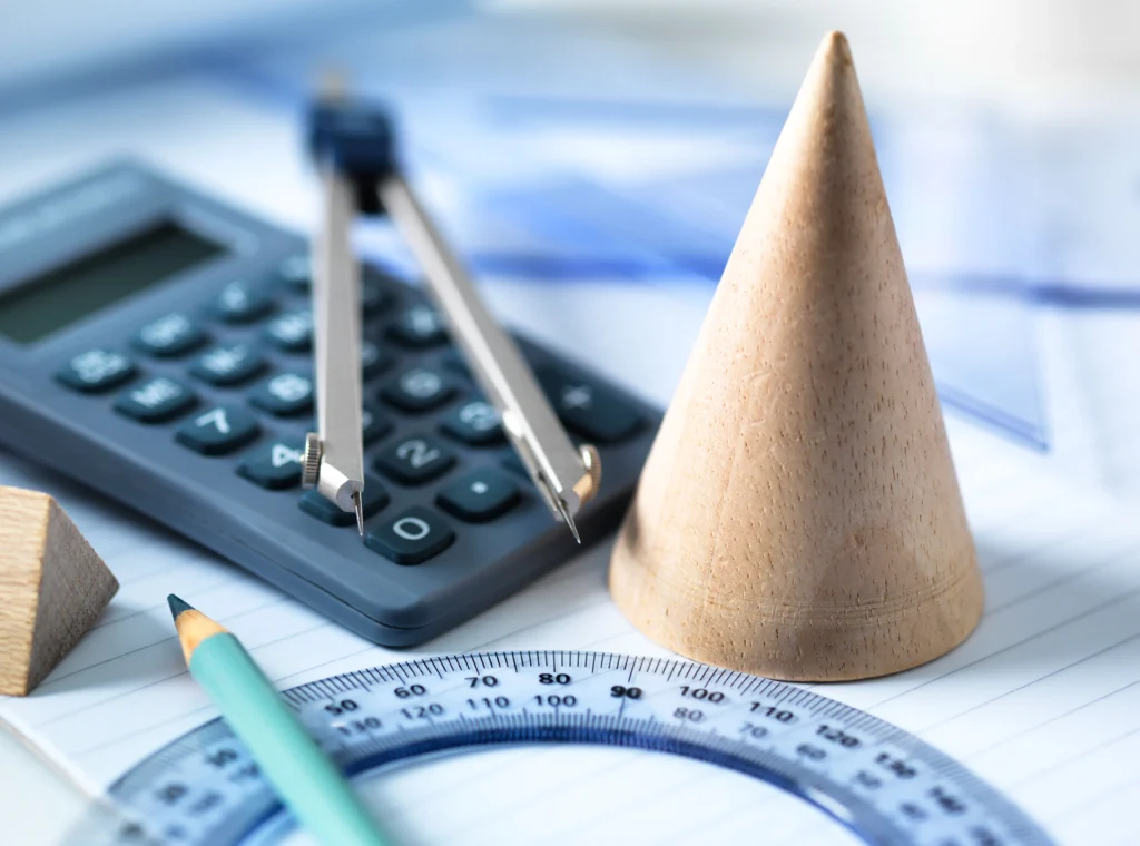 A wooden cone, protractor, pencil, compass, and calculator are arranged on graph paper.