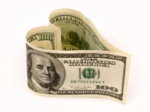 A folded one hundred dollar bill shaped into a heart.