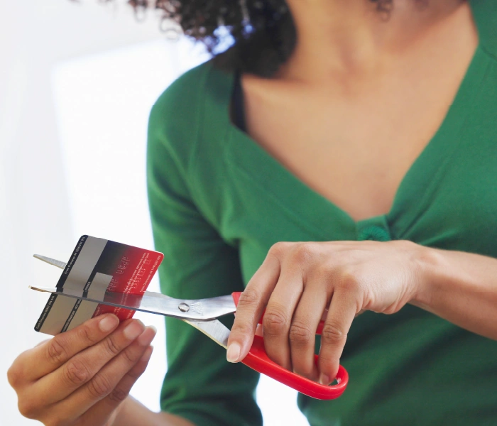 A person using scissors to cut a credit card in half.