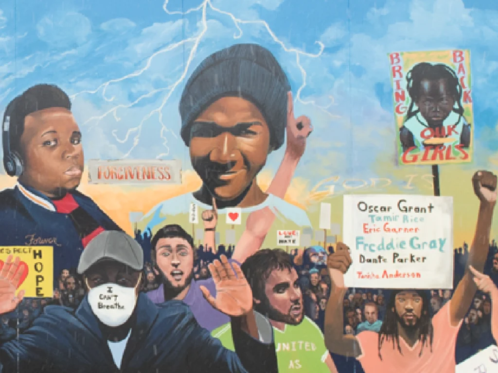 Mural depicting diverse people protesting, holding signs with names like Oscar Grant and Eric Garner and messages like "I can't breathe" and "Bring back our girls.